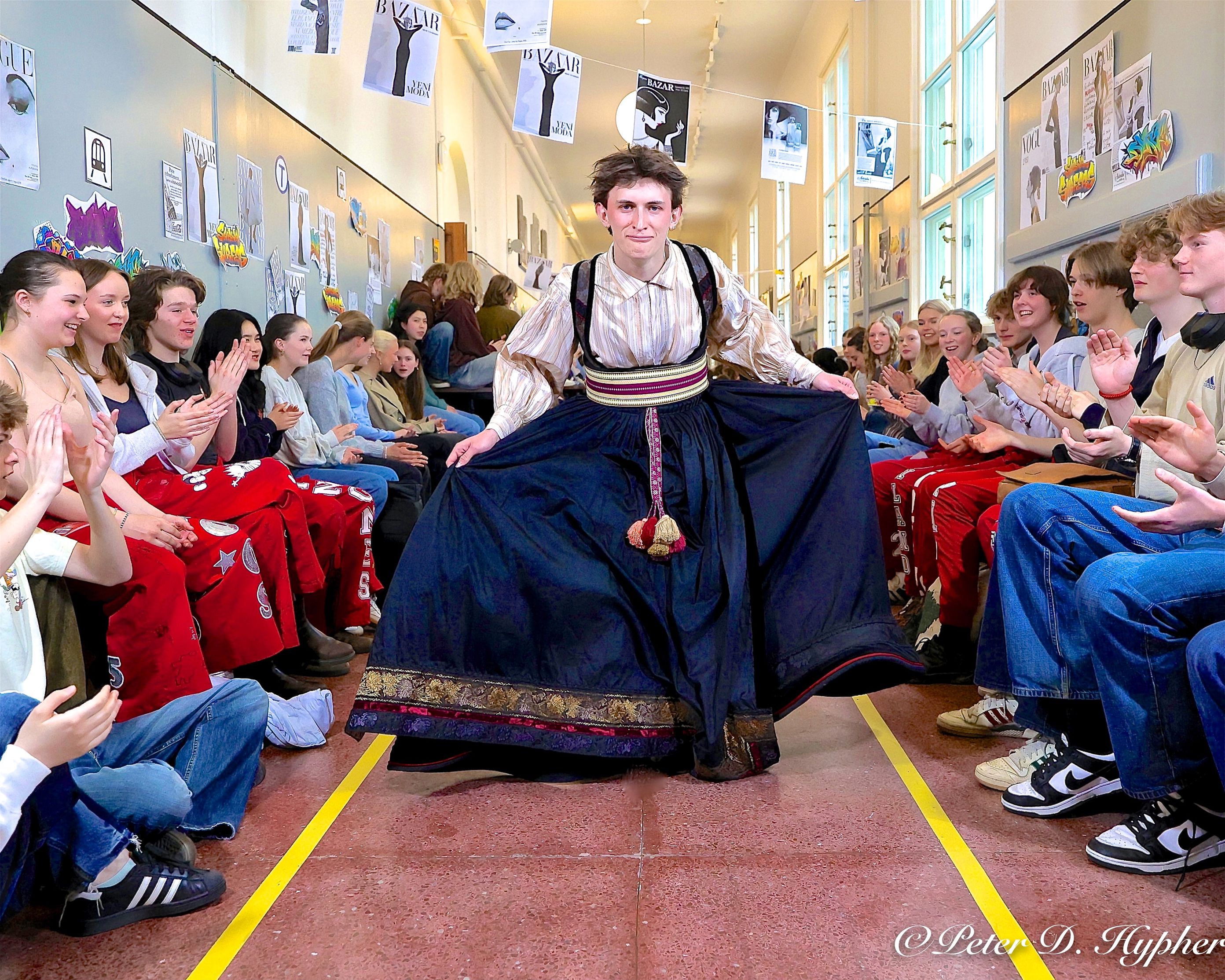 En person i tradisjonell drakt som danser foran en folkemengde