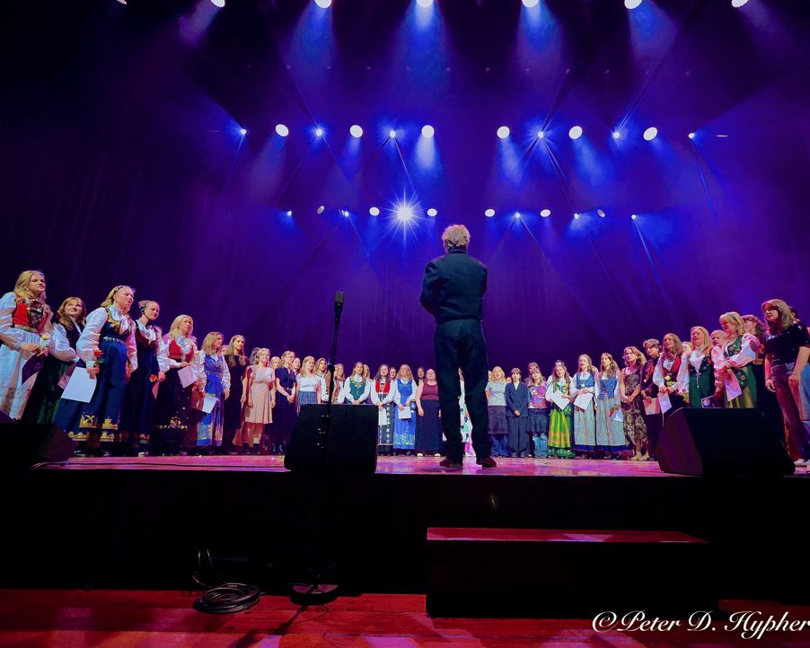 en person som står på en scene med en gruppe mennesker foran seg
