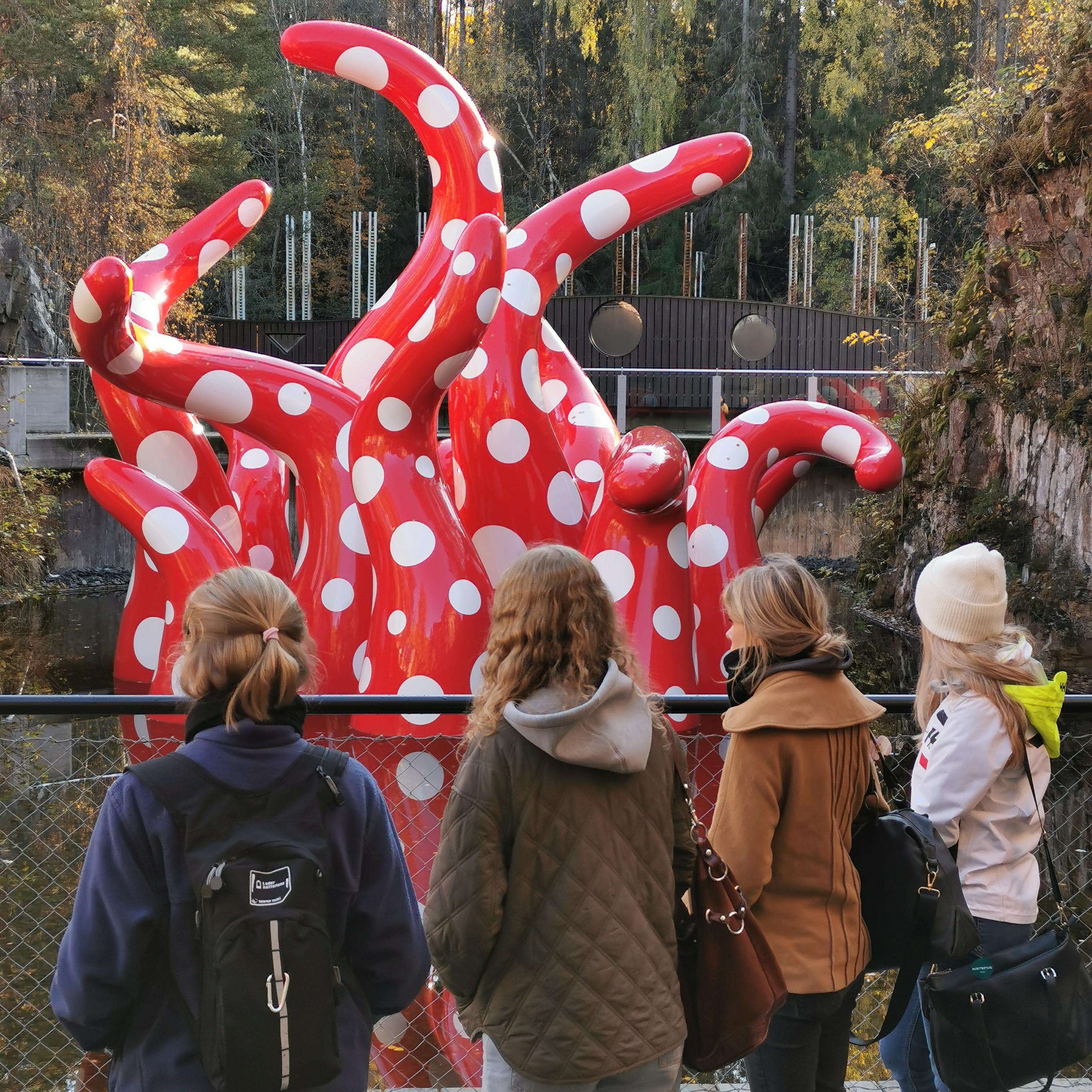 En gruppe mennesker som ser på en statue av en rød drage