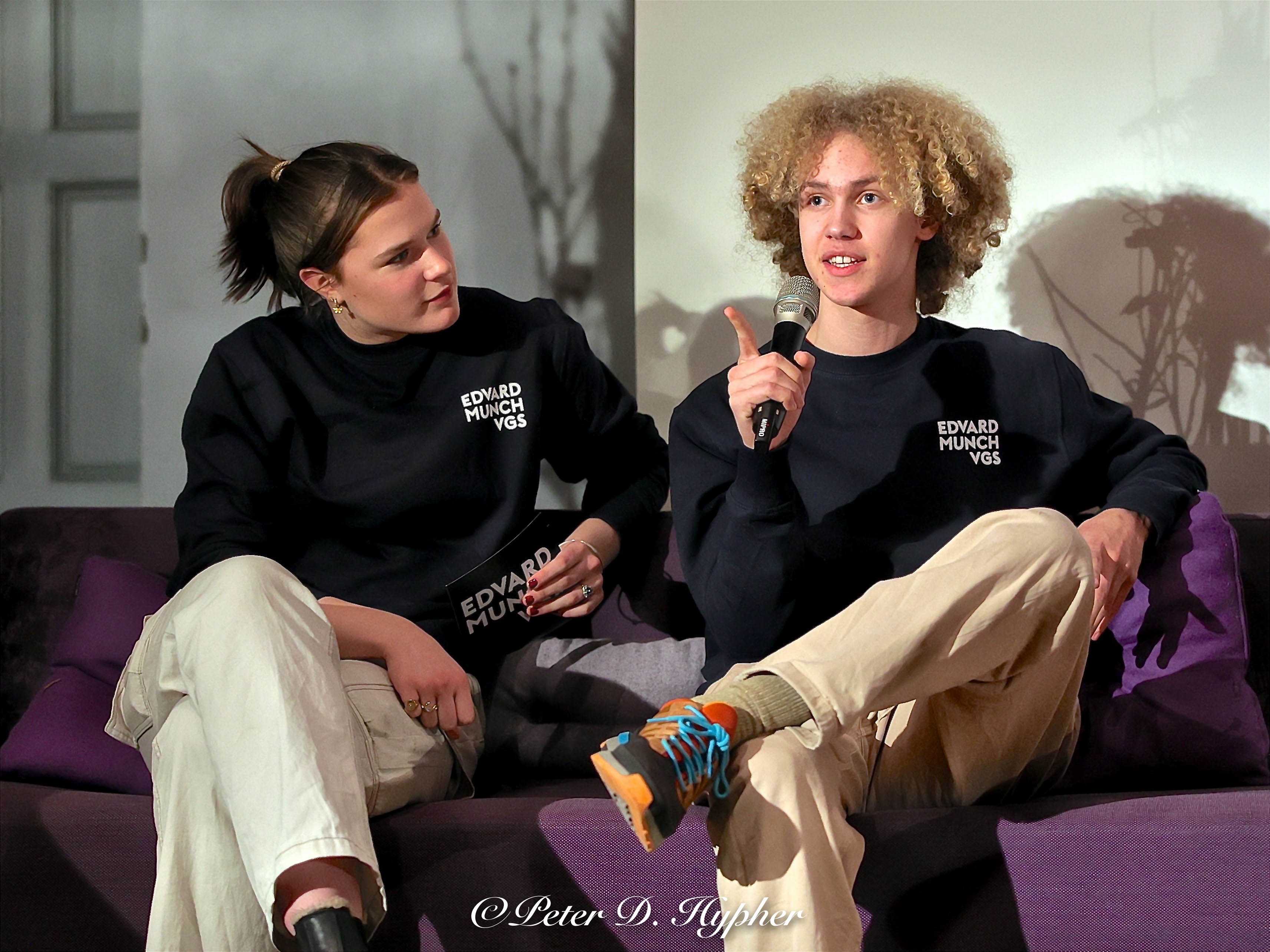 et par personr som sitter på en sofa med en mikrofon